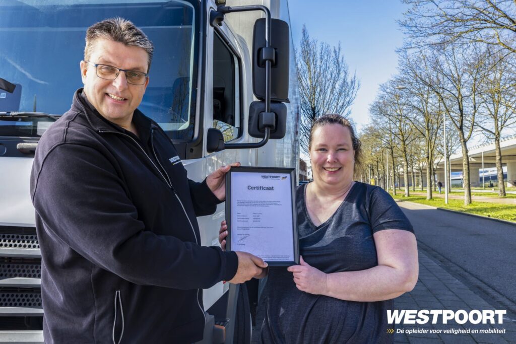 Cursist ontvangt certificaat voor Slimme tachograaf van Westpoort instructeur voor een vrachtwagen op een Westpoort trainingslocatie.